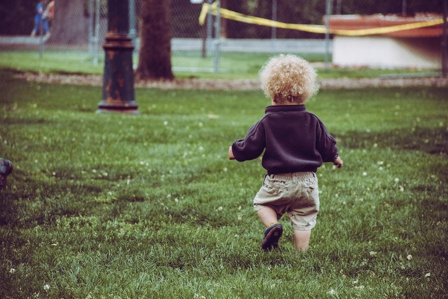 Baby walking away with a black long-sleeve woven shirt