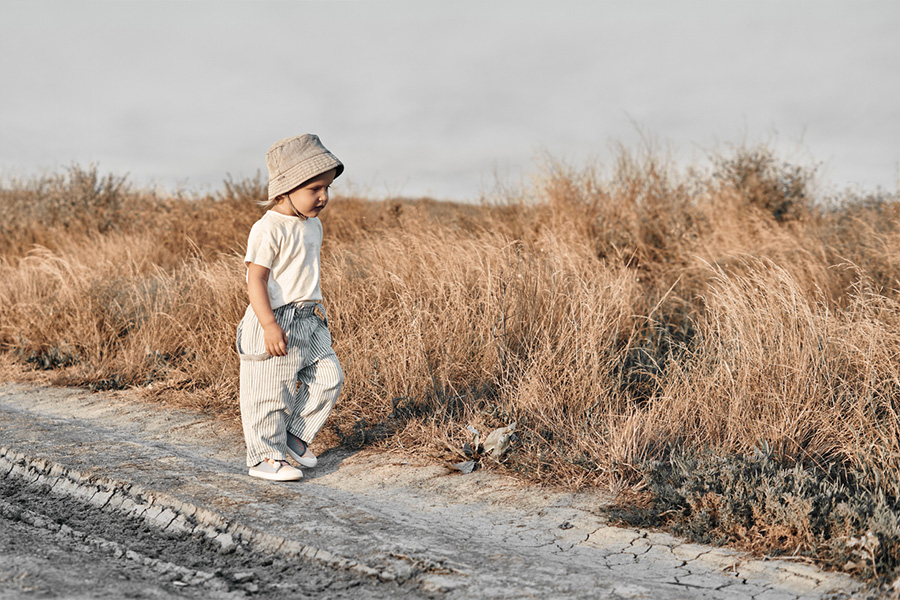 Bambino che cammina lungo una strada in pantaloni rilassati