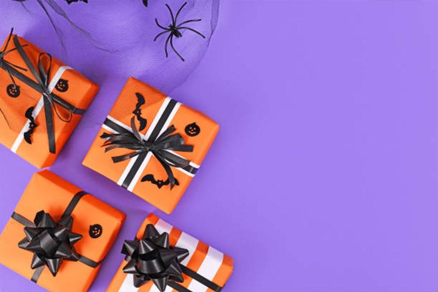 Schachteln mit Halloween-Thema, verpackt in orangefarbenem Papier mit schwarzen Schleifen