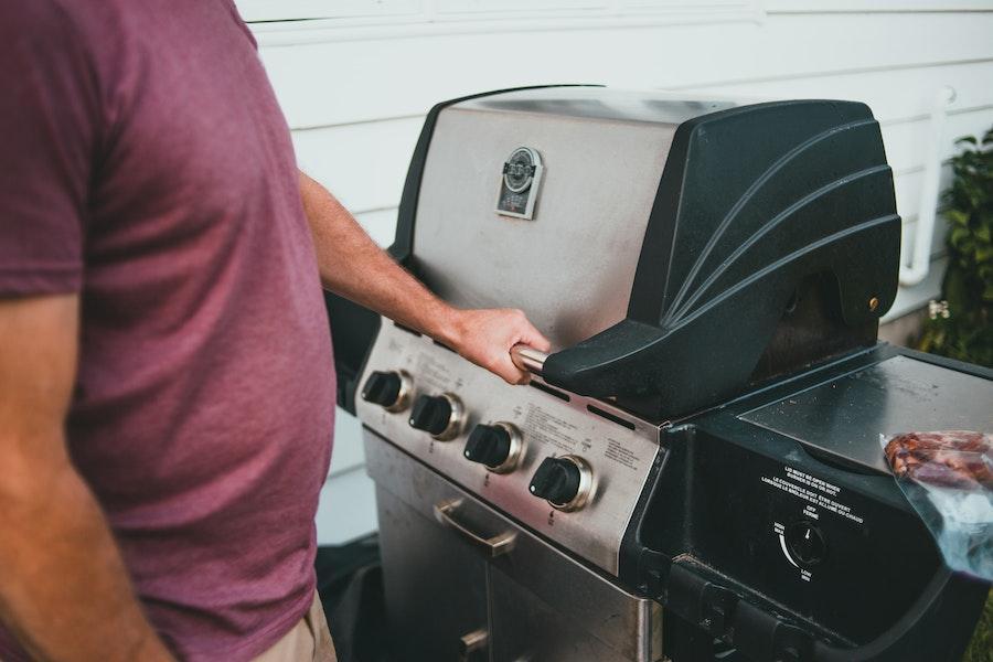 Hombre sujetando el asa de una parrilla ahumadora