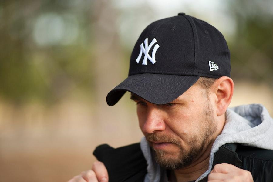 Hombre posando con una gorra de béisbol negra de 5 paneles