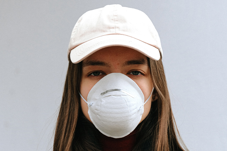 Mujer enmascarada con una gorra de béisbol precurvada blanca