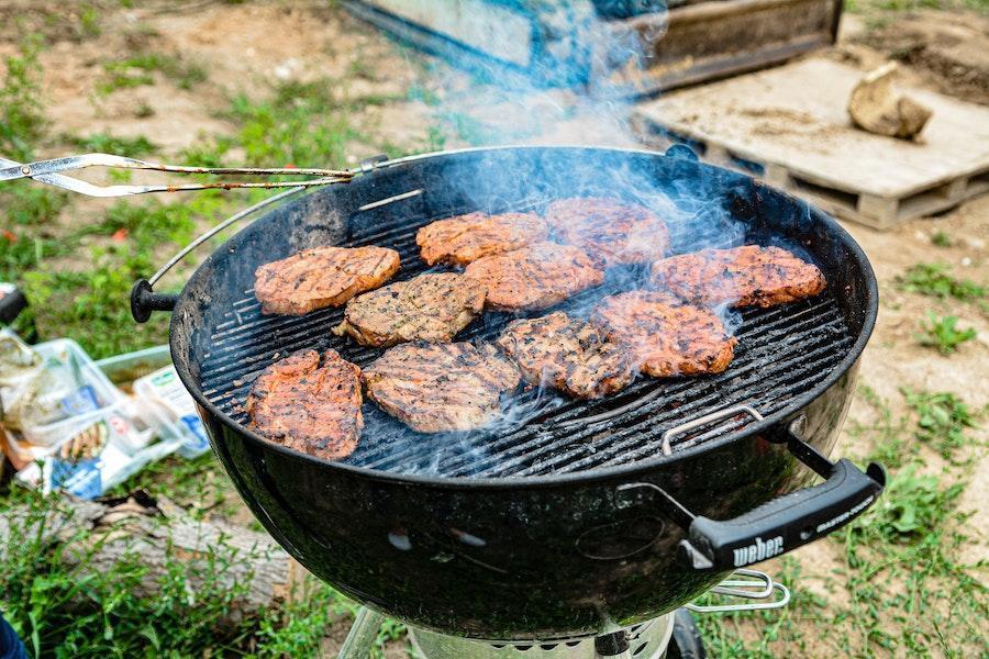 Cocinar carne en parrilla de carbón de barril