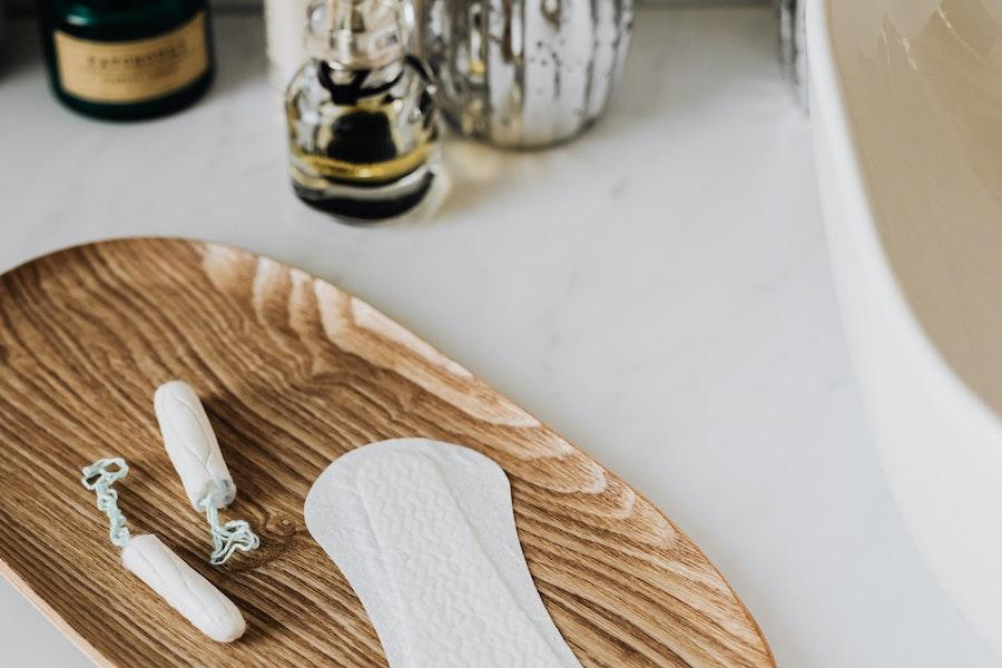 Sanitary pad and tampons placed on a wooden tray