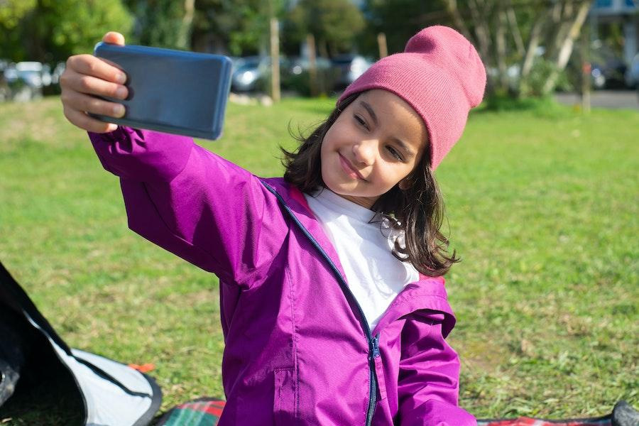 Tween tersenyum sambil berfoto selfie di luar ruangan