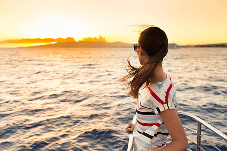 ボート上の夕暮れ時に縞模様の T シャツを着た女性