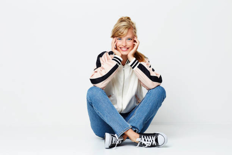 Woman wearing white and pink letterman jacket sitting on ground