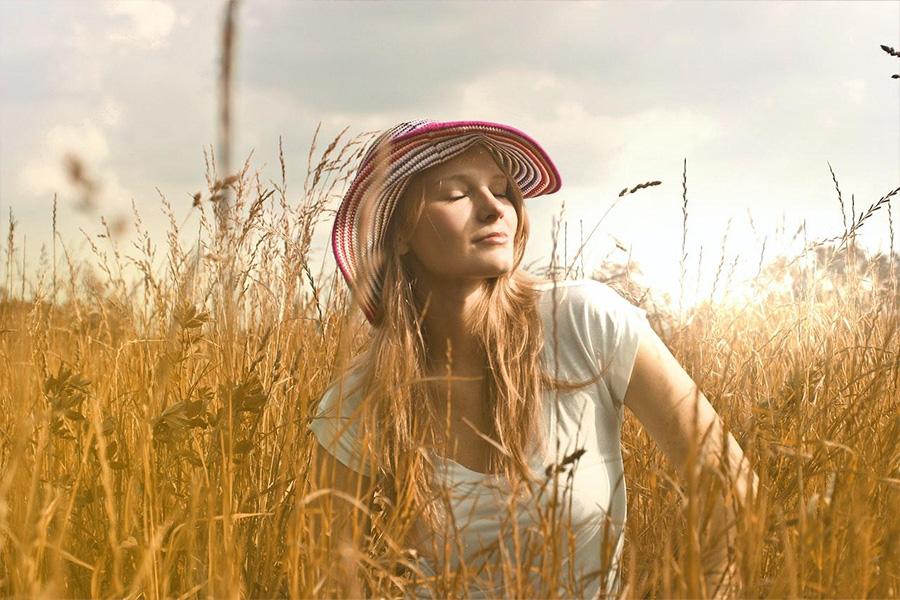 Femme portant un haut blanc et un chapeau rouge et blanc assis dans les hautes herbes