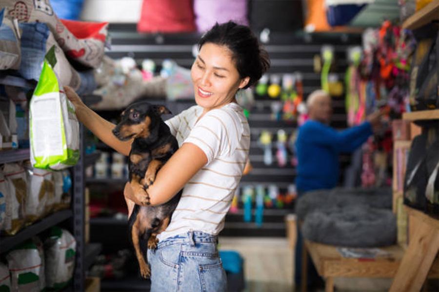 Mulher com cachorro segurando um grande saco de comida de cachorro