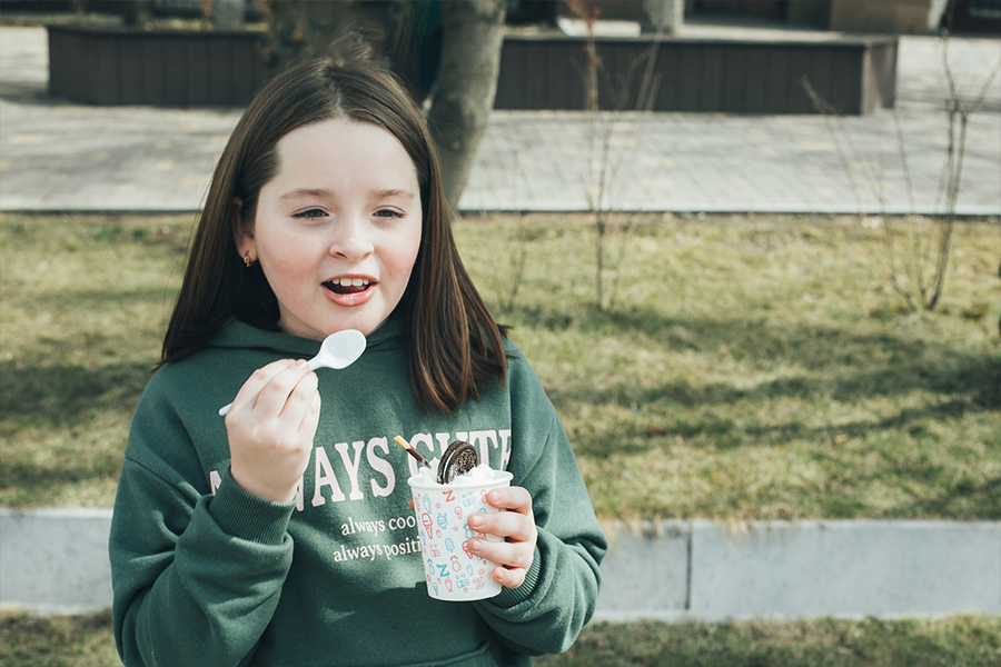 Chica joven con una sudadera gráfica mientras come helado