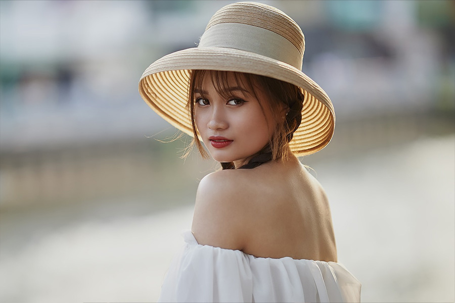 A cute lady in a white off-shoulder top and a straw hat