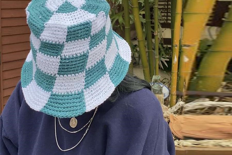 Cappello a secchiello a scacchi blu e bianco che copre il volto di una donna