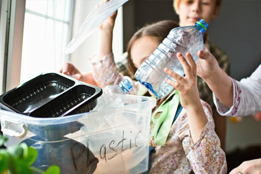 Enfant plaçant une bouteille d'eau usagée dans un récipient en plastique