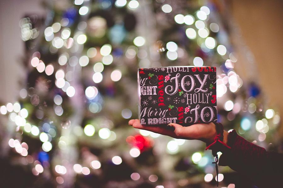 Mão segurando um presente de Natal em uma festa de férias