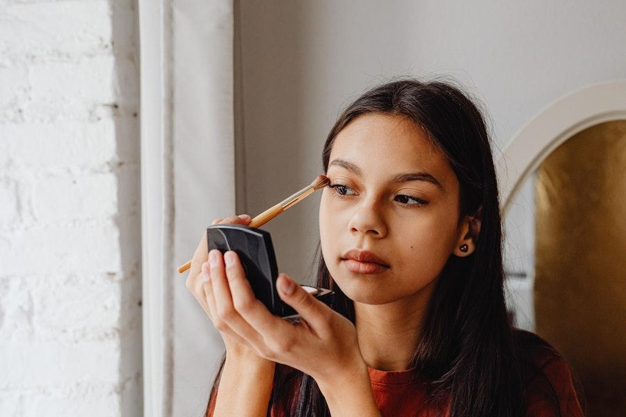 Dame à l'aide d'un pinceau de maquillage pour appliquer le fard à paupières