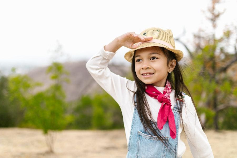 Gadis kecil mengayunkan topi ember rajutan