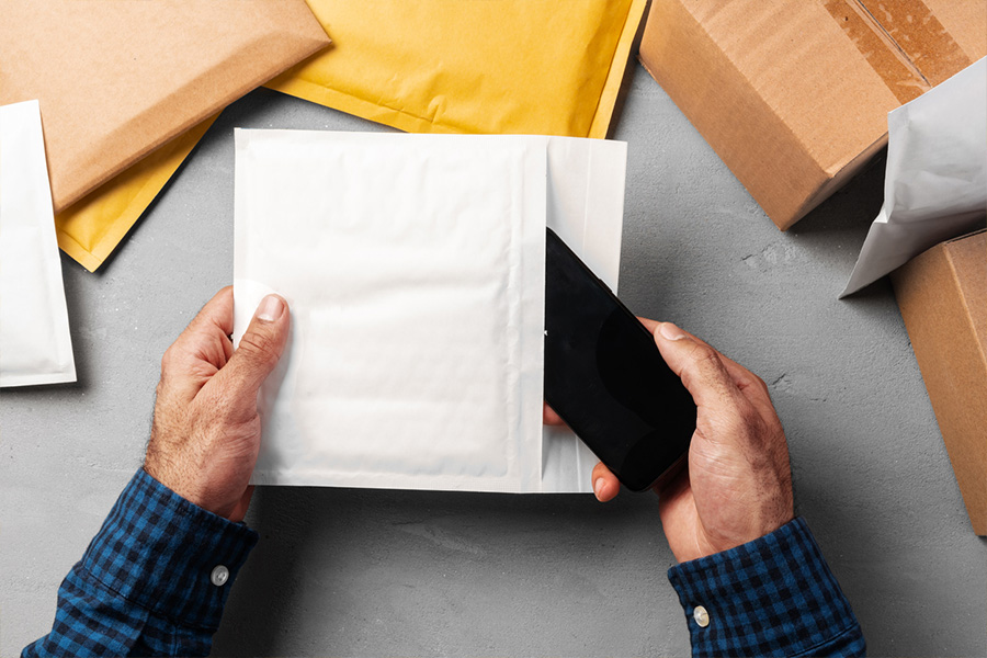 Mãos masculinas embalando envelopes bolha amarela para envio