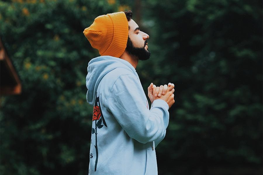 Homem olhando para o céu com um boné de relógio amarelo