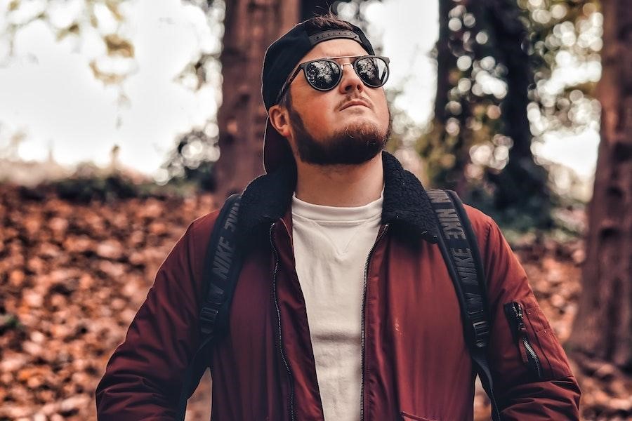 Uomo in posa in una foresta con un cappello snapback