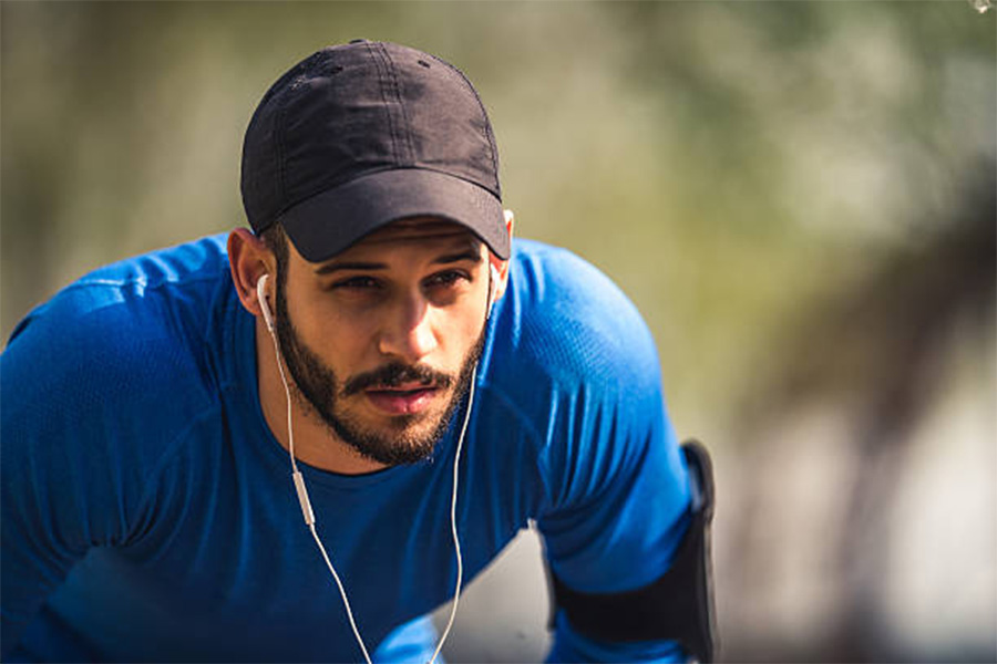 Uomo che si prende una pausa dalla corsa indossando un cappello da corsa nero