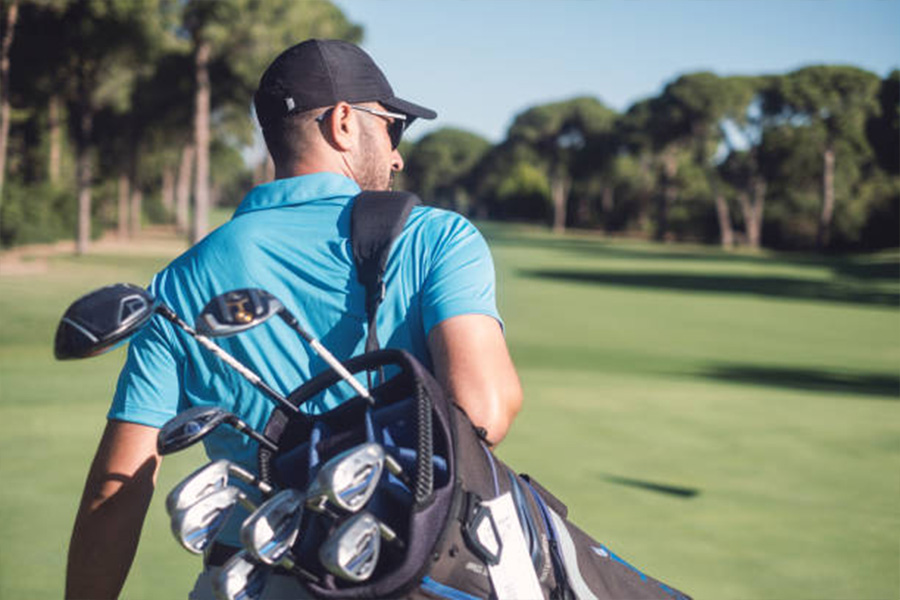 Uomo che cammina sul campo da golf indossando un cappello da golf