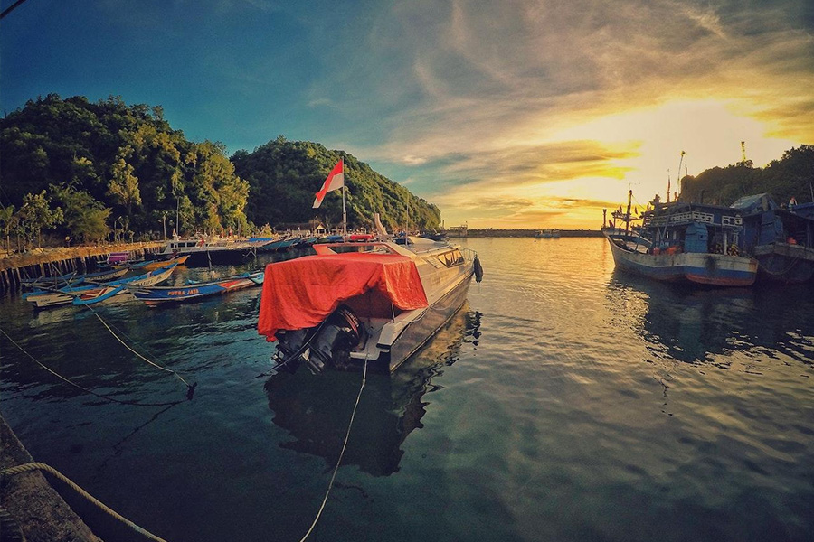 Motoscafo con bandiera indonesiana vicino al molo durante il tramonto