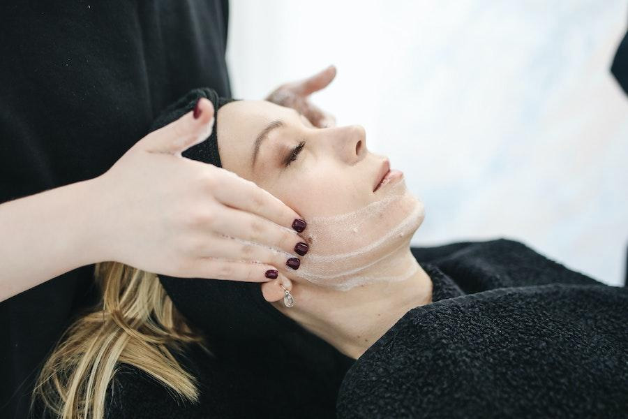 Mujer relajante aplicando crema en un spa