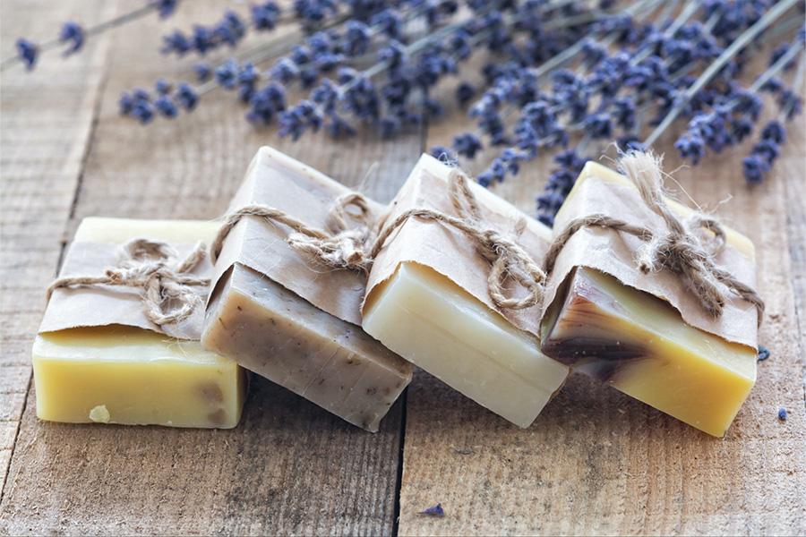 Simple soap bars wrapped in recyclable packaging sitting on wood table