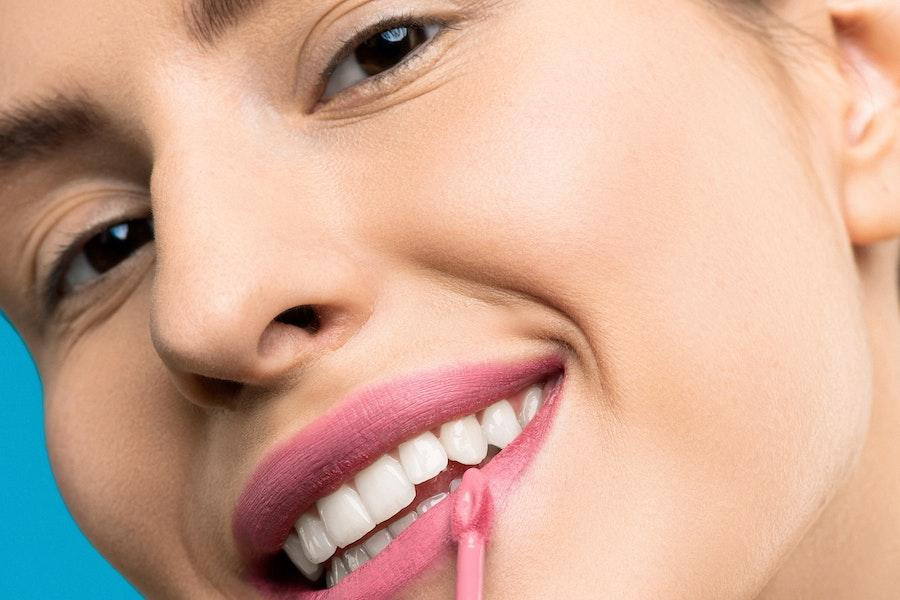 Femme souriante portant une teinte de rouge à lèvres rose