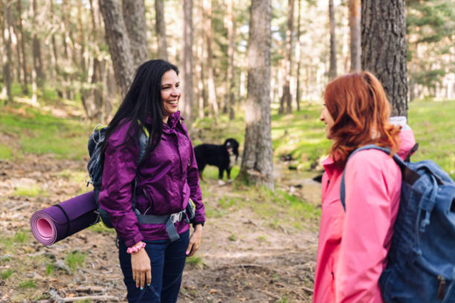 Zwei Frauen im Wald mit leichten Jacken und Yogamatten