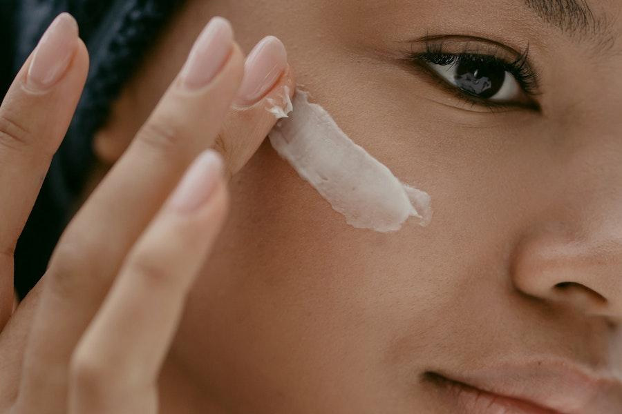 Mujer aplicando crema para el cuidado de la piel en la cara