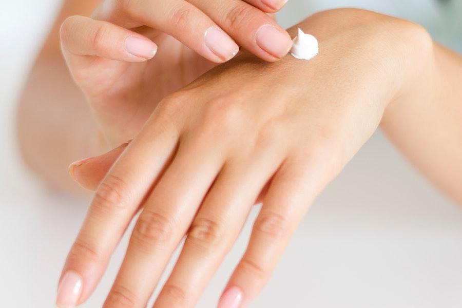 woman applying skincare cream on her hand