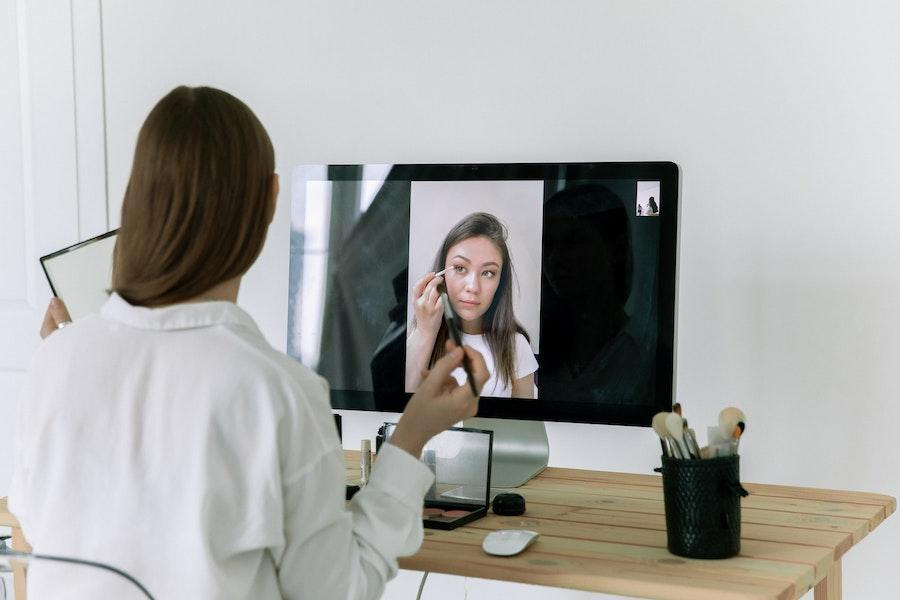 woman following a makeup tutorial on a large screen