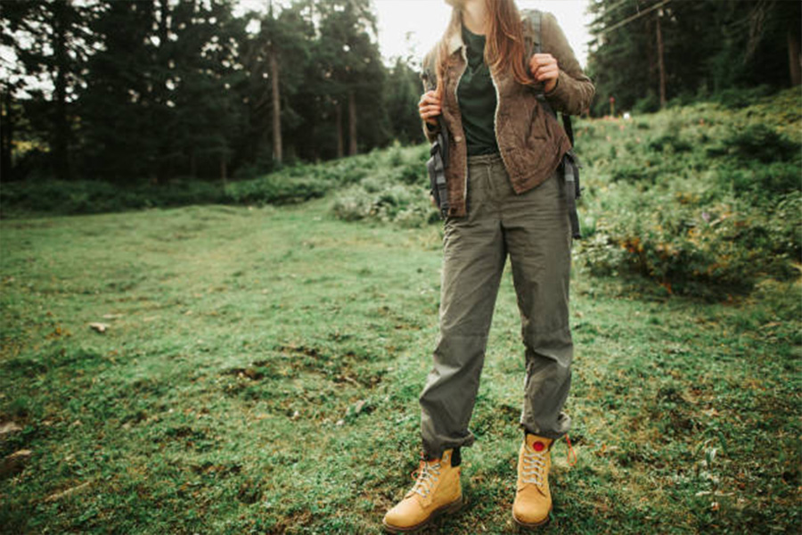 Mujer haciendo senderismo con pantalones de aventura y botas grandes en primavera