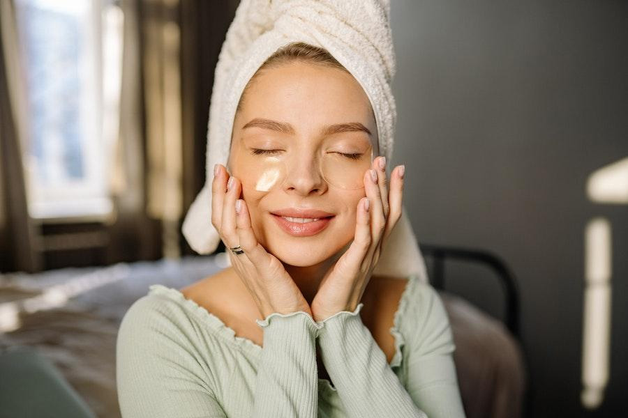 woman holding her face while using eye patches