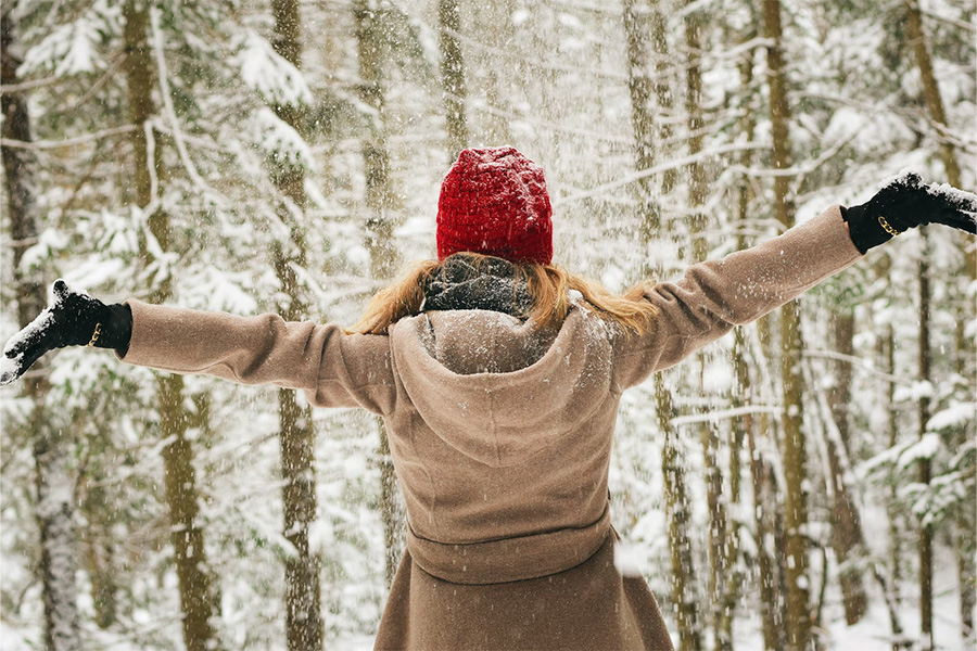 Femme dans une forêt enneigée portant un bonnet rouge