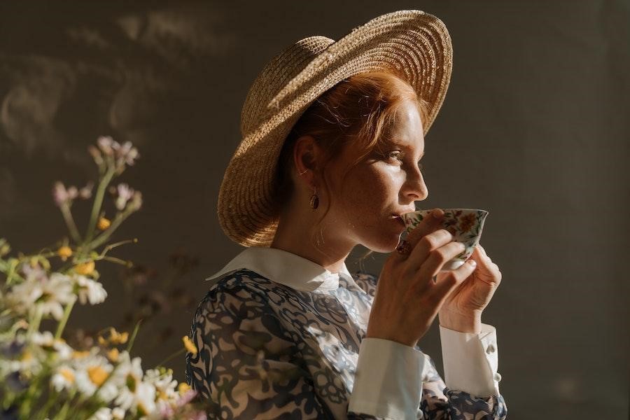 Frau mit Strohhut trinkt Kaffee