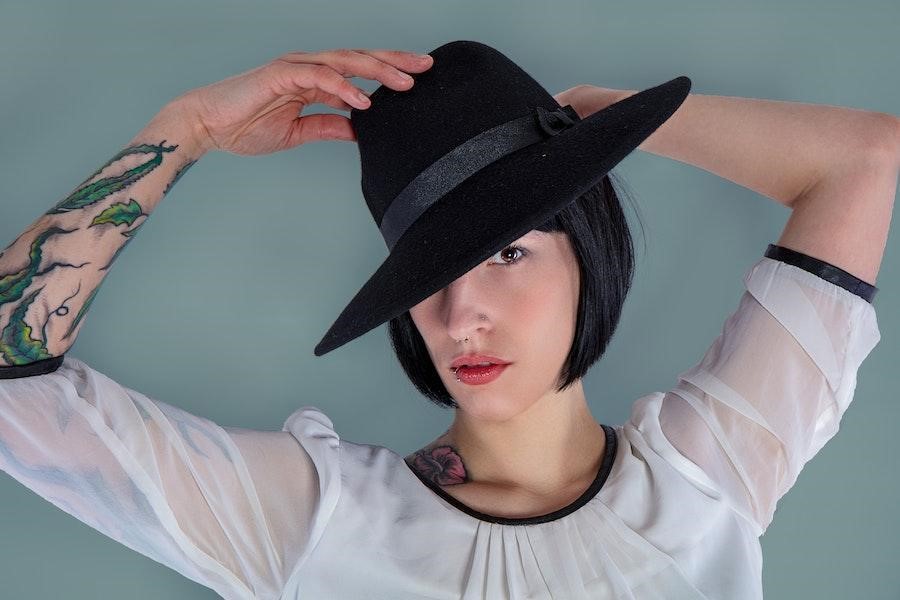 Femme dans une manche longue blanche avec un fedora noir