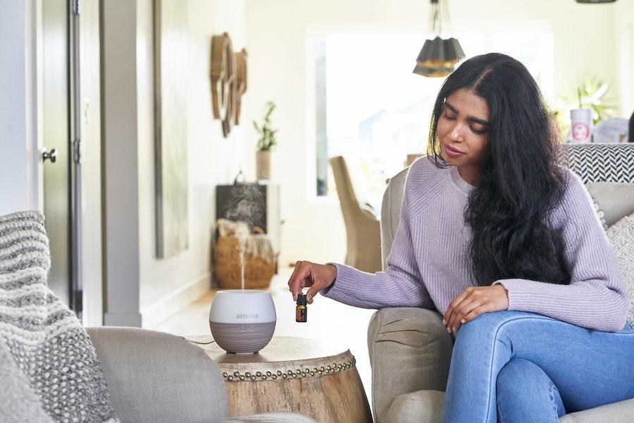 Donna che posiziona l'olio profumato vicino a un diffusore di aromi