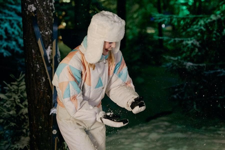 Woman playing with snow in a white ushanka hat