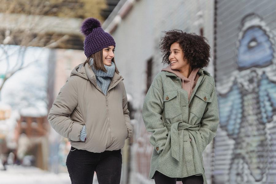 Woman rocking a pom-pom beanie talking to another woman