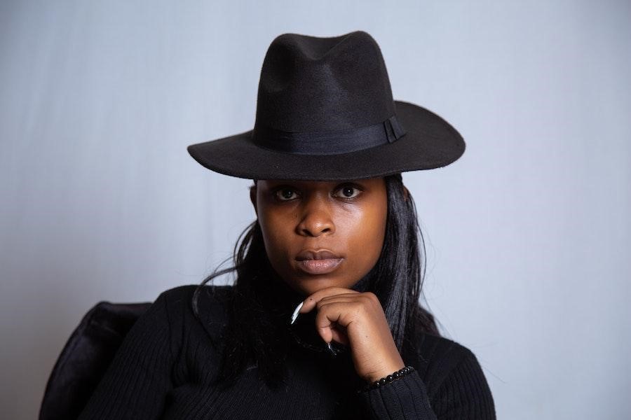 Femme prenant la pose avec un fedora noir