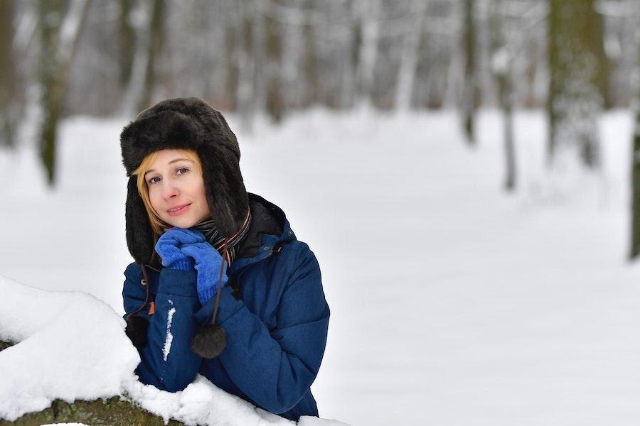 Donna seduta sulla neve con un cappello da trapper nero