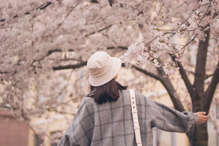 白いバケットハットをかぶった木の下にいる女性