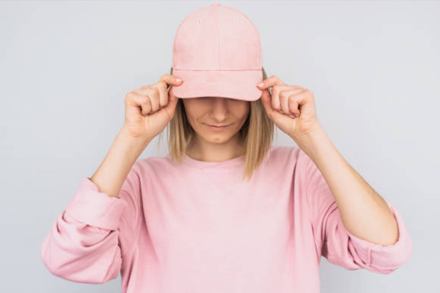 Femme portant une casquette de baseball rose et un pull rose