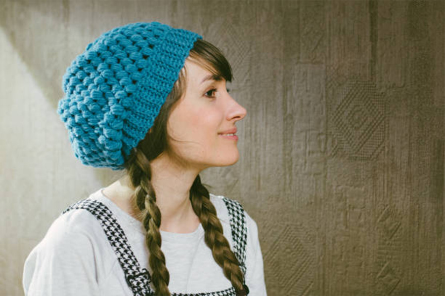 Femme portant un bonnet au crochet bleu chaud avec des tresses