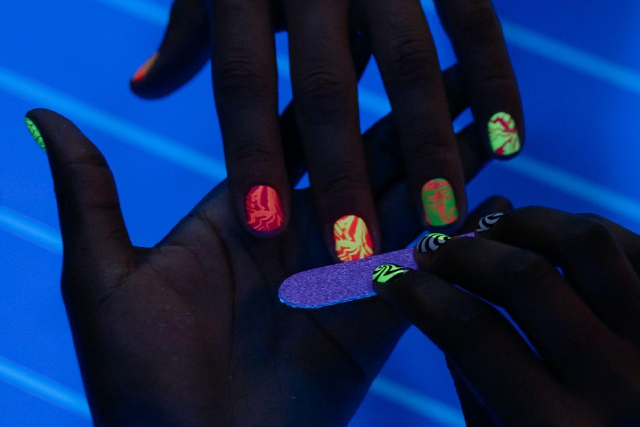 Mão de mulher com esmalte blacklight.