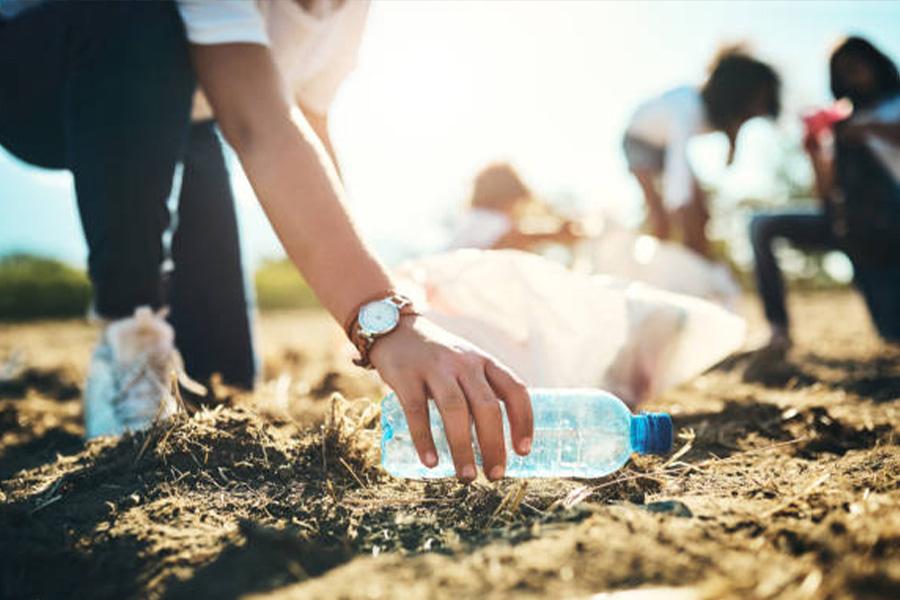 عامل يجمع زجاجة بلاستيكية من الأرض