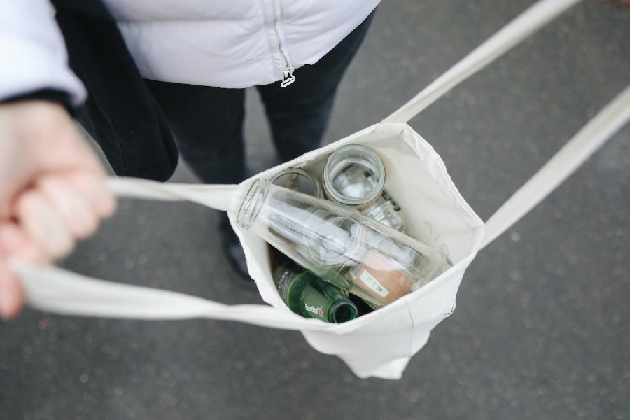 Una signora che tiene una borsa con bottiglie vuote