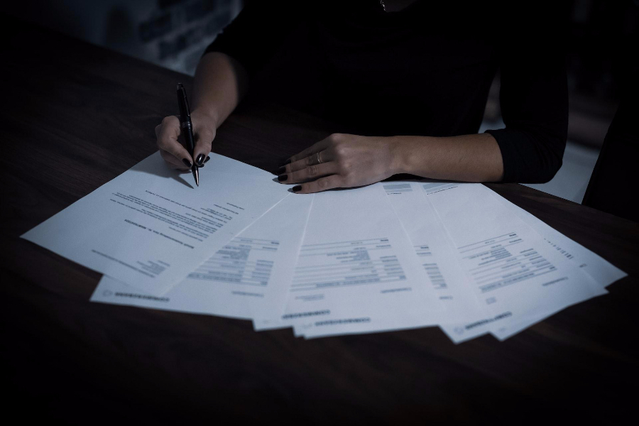 A lady signing several documents with a ballpoint pen